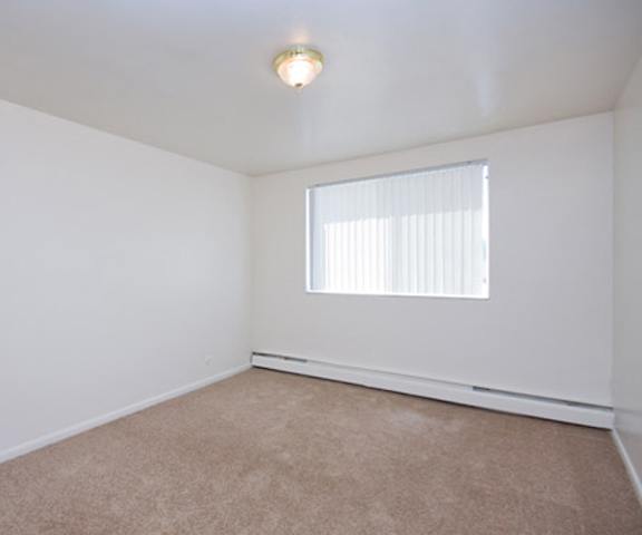An empty bedroom with a window at Bristol Square Apartments.