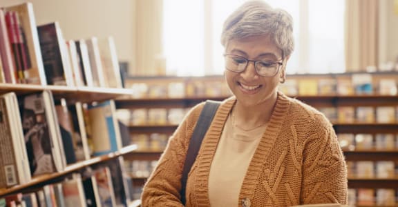 A woman is reading a book in a library.