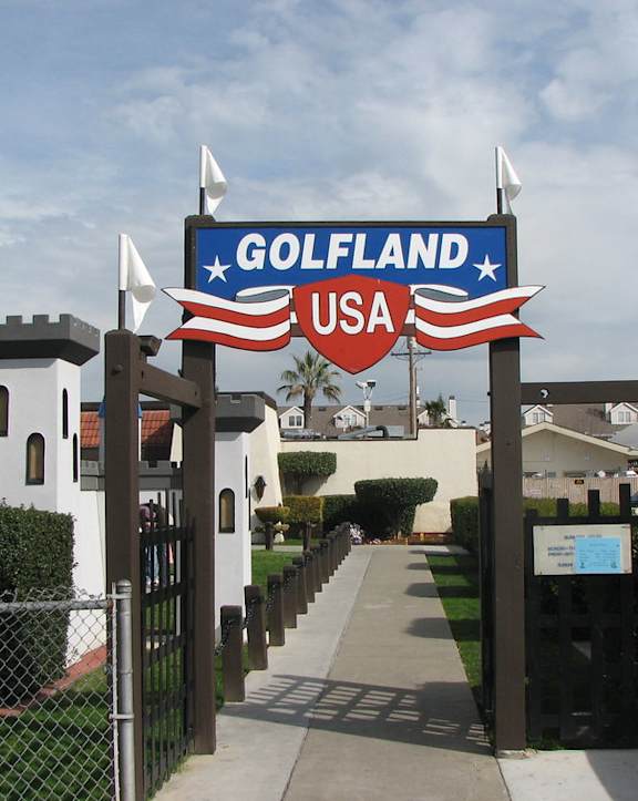 A sign that says Golfland USA is in front of a fence.