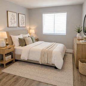 A bedroom with a bed, nightstand, and a window with blinds.