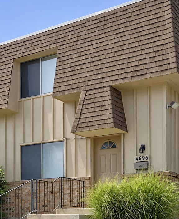 A house with a brown roof and a white wall with a number 4696 on it.