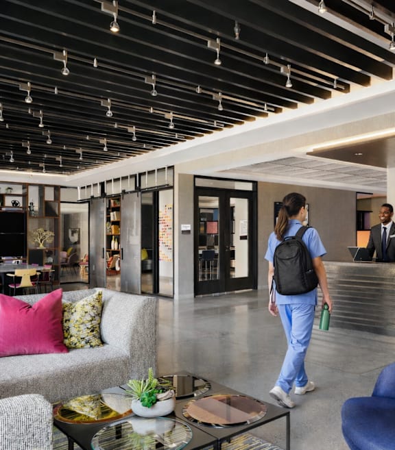 A woman with a backpack walks into a reception area.