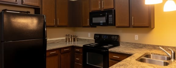 a kitchen with a black refrigerator freezer next to a stove top oven