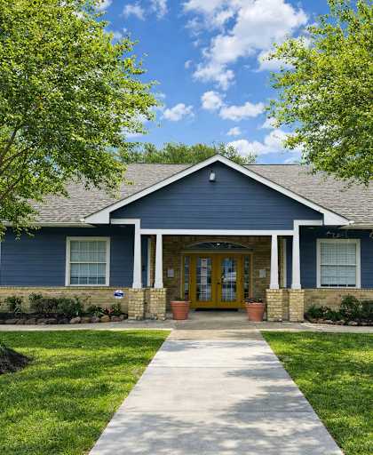 A blue building with a yellow door and a white walkway in front.