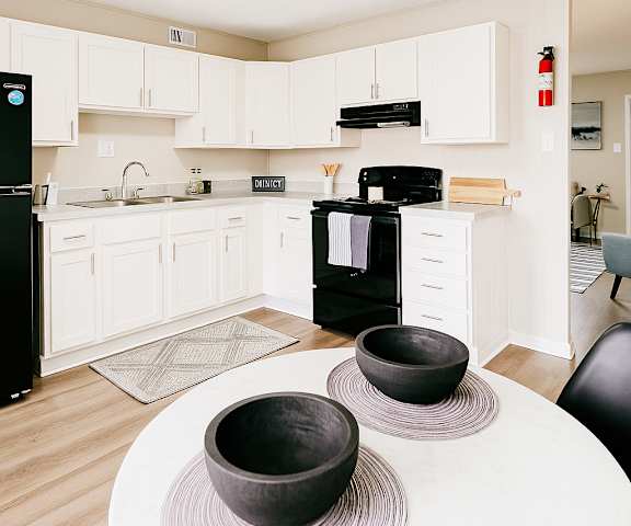 A black refrigerator sits in a kitchen with white cabinets and a black oven.