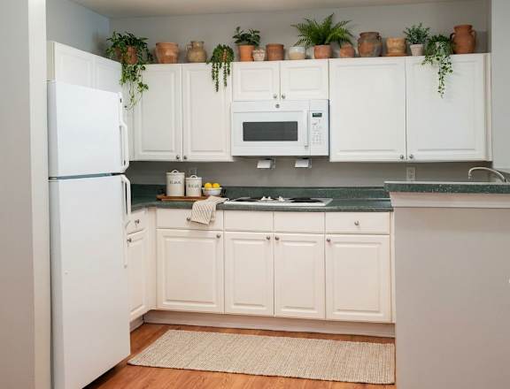 A kitchen with white cabinets and a white refrigerator.