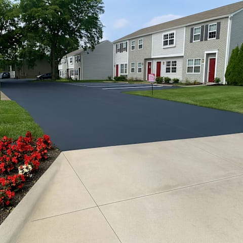 A long driveway leads to a building with a red door.