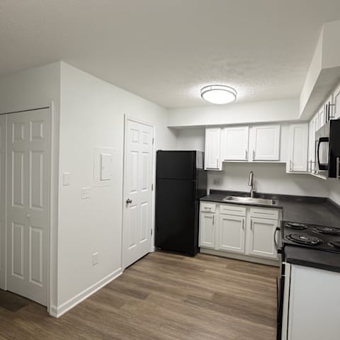 A kitchen with black appliances and white cabinets.