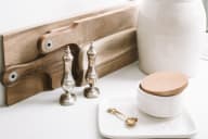 a white plate with wooden spoons and a wooden cutting board on a white table