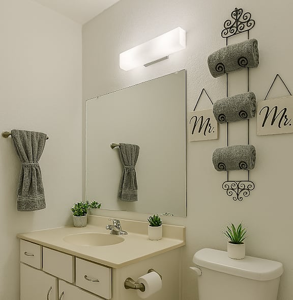 A bathroom with a white toilet, sink, and cabinets.