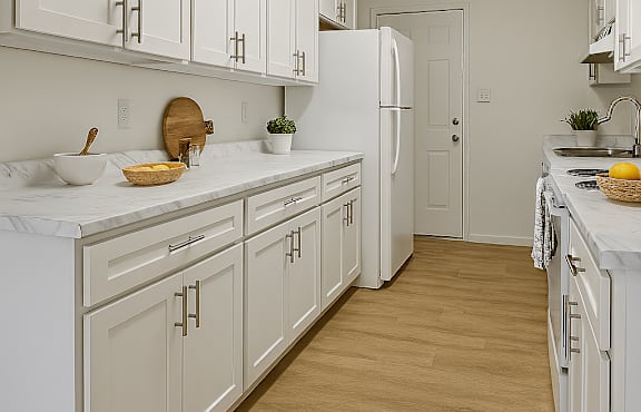 A white kitchen with wooden floors and a refrigerator.