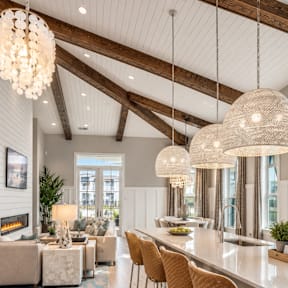 A modern kitchen with a long white island and wooden floors.