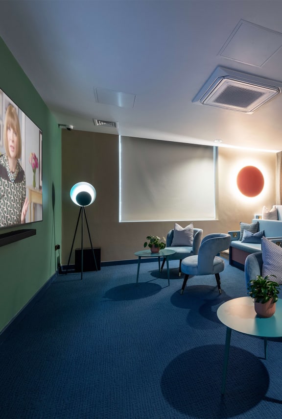 a living room with couches and chairs and a projector screen