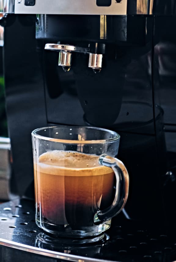 a cup of coffee being brewed in a coffee maker