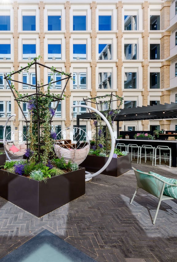 a courtyard with plants and chairs and a building in the background