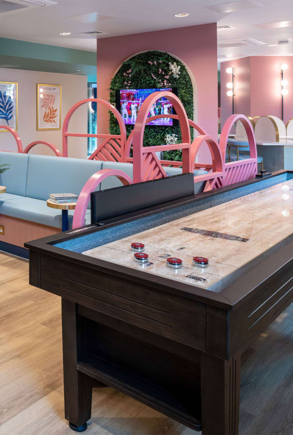 a pool table in a party room with pink and blue furniture