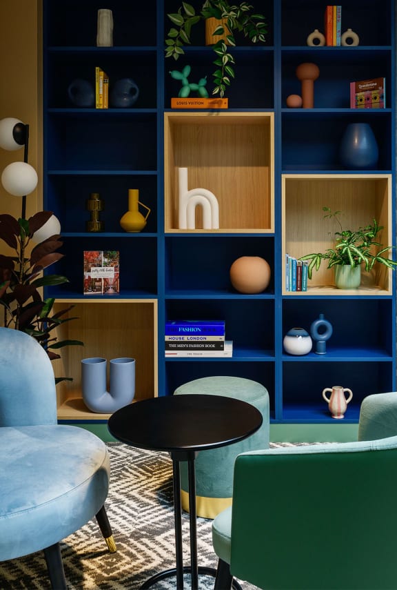 a living room with blue shelves and a table and chairs