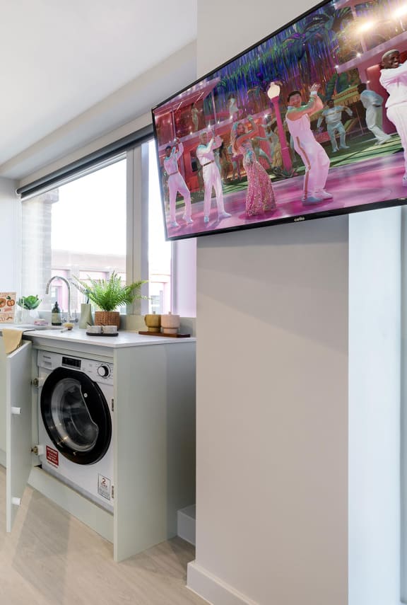 a kitchen with a washing machine and a television on top of a wall