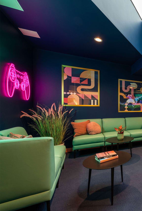 a room with green couches and a coffee table and a neon sign