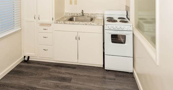 A kitchen with white cabinets and a wood floor.