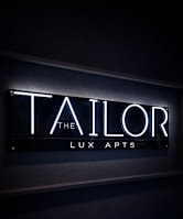 A neon sign that says "The Tailor Lux Apts".