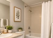 Thumbnail 11 of 11 - A white bathroom with a toilet, sink, and shower at Lifestyle at Shreveport in Shreveport, LA, 71109.