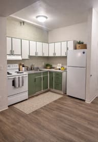 A kitchen with white cabinets and a white refrigerator.