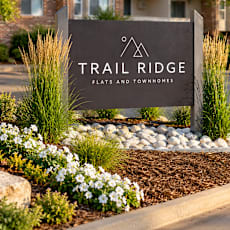 A sign for Trail Ridge flats and townhomes in front of a building.