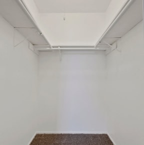 a walk in closet with white walls and two wooden rods hanging from the ceiling