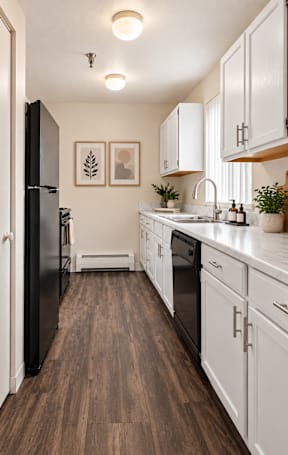 A kitchen with black appliances and white cabinets.