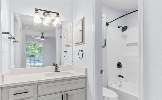A white bathroom with a sink, mirror, and toilet.