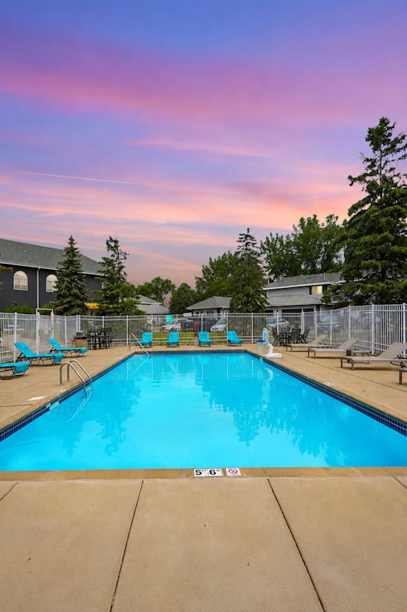 A large swimming pool surrounded by a fence and chairs.