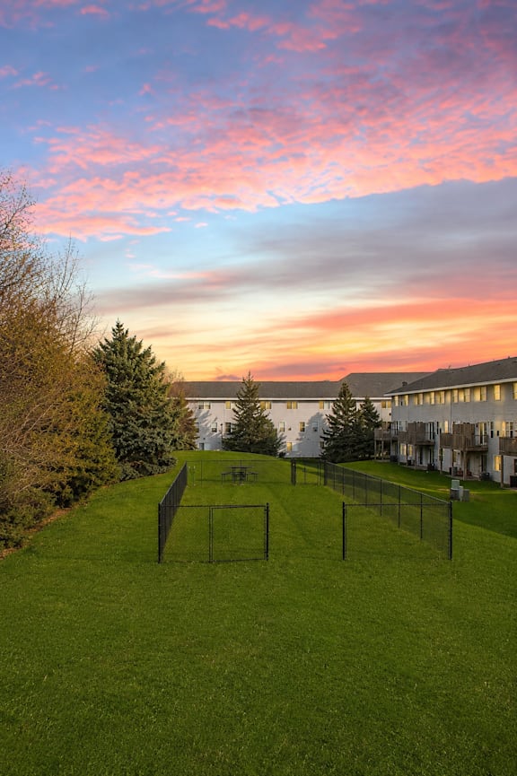 A beautiful sunset view of a grassy field with a building in the background.