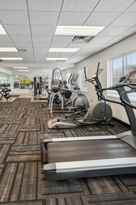 A gym with a variety of equipment including treadmills, weights, and exercise machines.