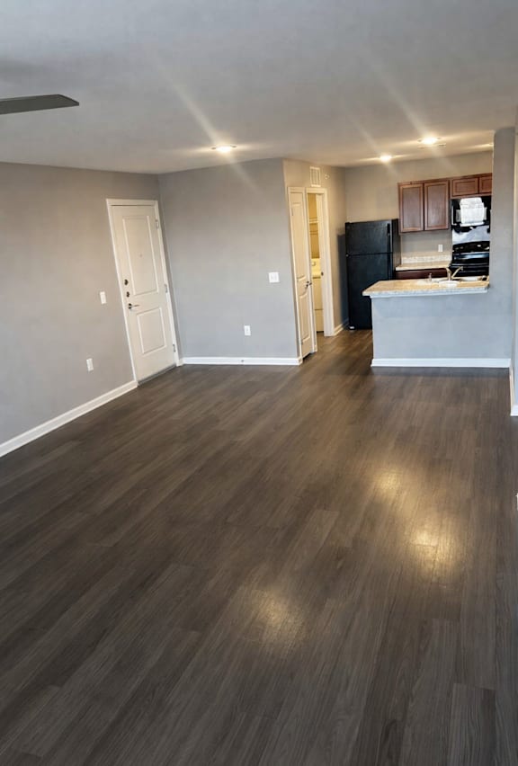 A kitchen with a refrigerator and cabinets is visible through an open door.