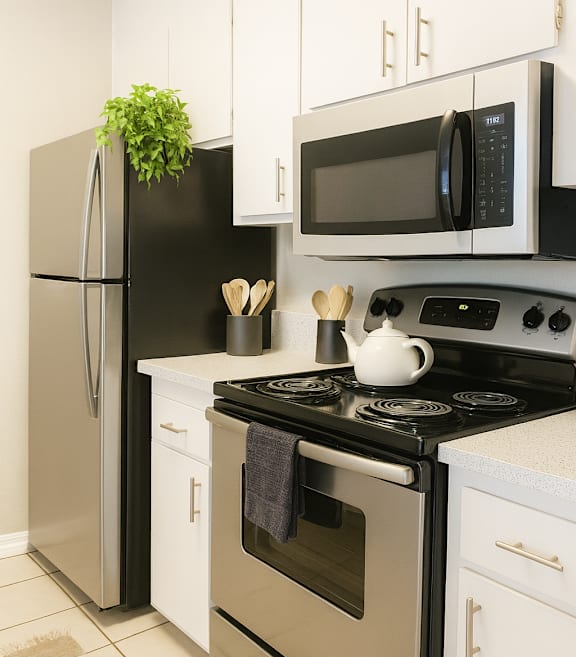 A black fridge and microwave in a white kitchen.