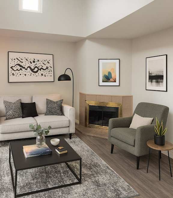 A living room with a white couch, a green armchair, a coffee table, and a fireplace.