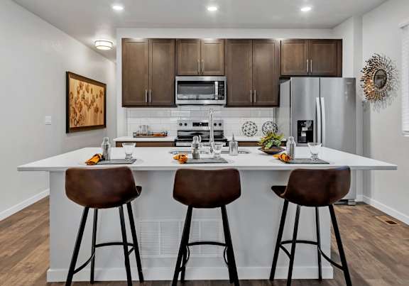 modern kitchen with island and stools in front of stainless steel appliances