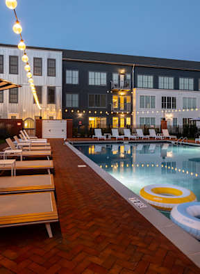 A pool with chairs and a building in the background.