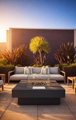 A patio with black chairs and a table is surrounded by plants.