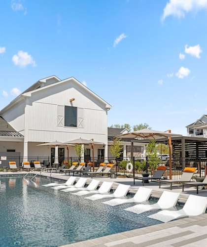 A pool with white lounge chairs and a white building with a black roof at Madison Prickett Preserve, Yardley