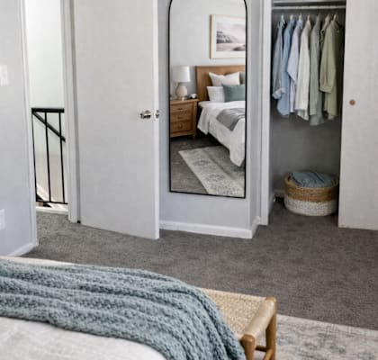 A bedroom with a bed, a wardrobe, and a mirror.