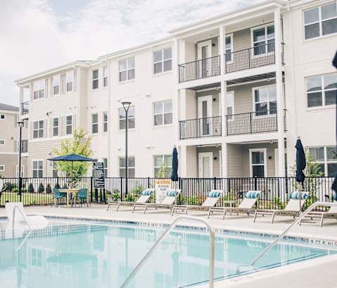 a swimming pool in front of an apartment building at Woodlands Creekside Apartments, McDonough, GA, 30253
