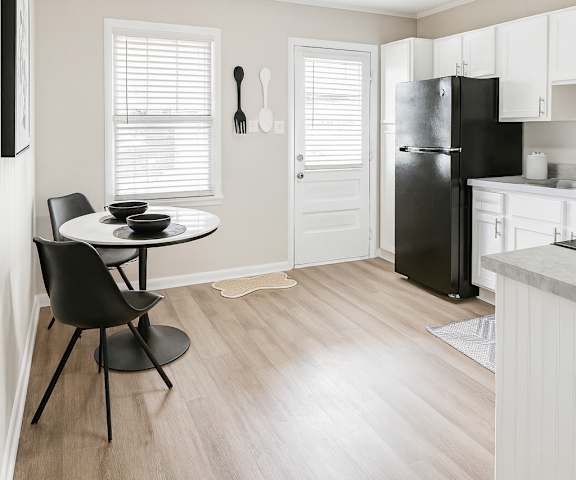 A kitchen with a black fridge and a dining table with two chairs.