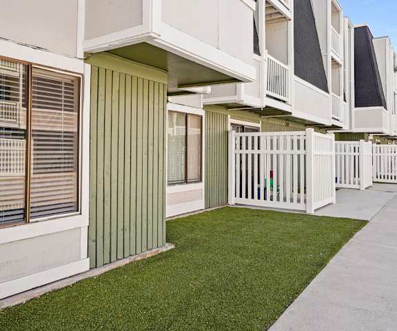 an exterior view of a row of apartments with grass and a sidewalk