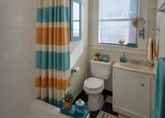 A bathroom with a white toilet, a striped shower curtain, and a striped rug. at Casa Del Rey Apartments, Oregon, 97209