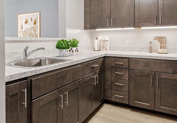 A kitchen with dark brown cabinets and a white sink.