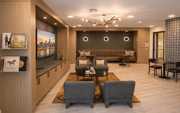 Apartment coworking space with modern seating, work tables, built-in cabinetry, and a TV in a shared lounge environment.