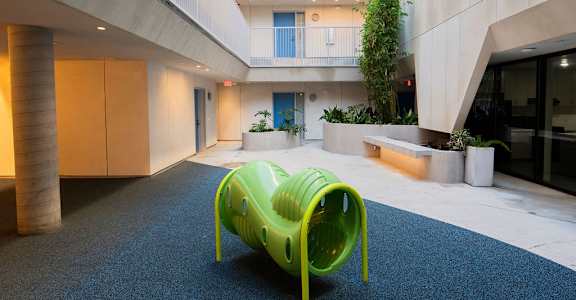 A bright green plastic chair sits on a carpeted floor in a modern building.