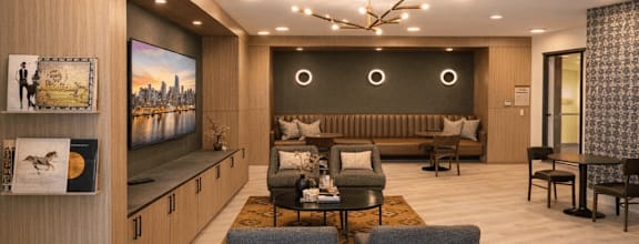Apartment coworking space with modern seating, work tables, built-in cabinetry, and a TV in a shared lounge environment.